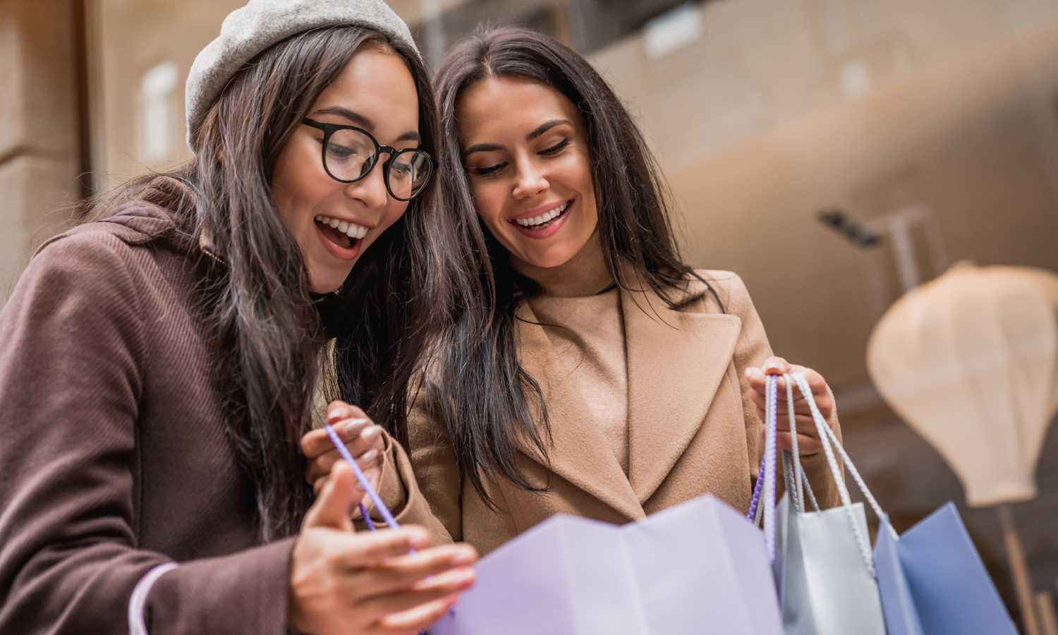 Two smiling women look into a shopping bag